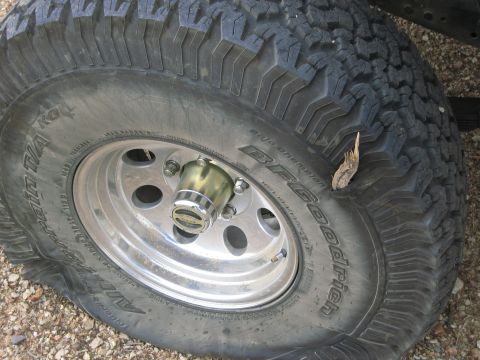 1986 Ford Bronco - A flat tire and wheel assembly is shown, with visible text on the tire and a website watermark.