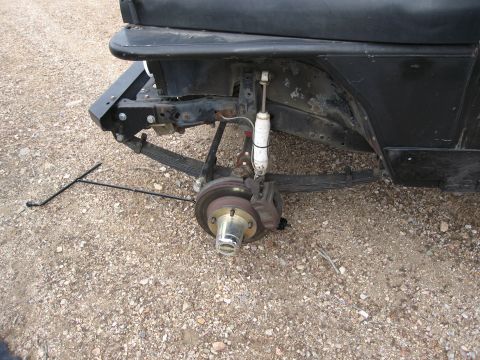 1986 Ford Bronco - Rear suspension components of a vehicle are visible, with the wheel removed and brake assembly exposed.
