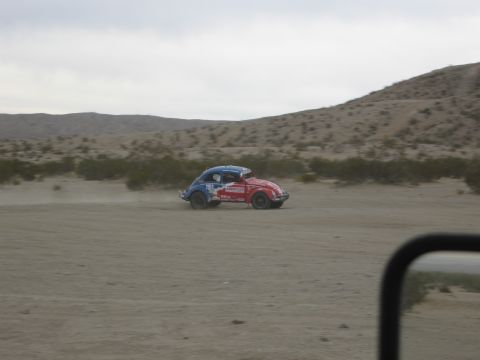 1986 Ford Bronco - A modified Volkswagen Beetle, painted in patriotic colors, kicks up dust as it races across a desert landscape.