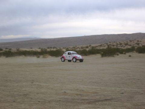 1986 Ford Bronco - Volkswagen Beetle races through a desert landscape under a cloudy sky.