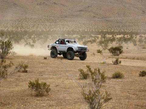 1986 Ford Bronco - A modified off-road vehicle navigates a dusty desert terrain, suggesting a race or off-road event.
