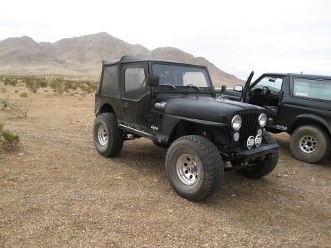 1986 Ford Bronco - Black Jeep CJ-7 and Ford Bronco parked in a desert environment.
