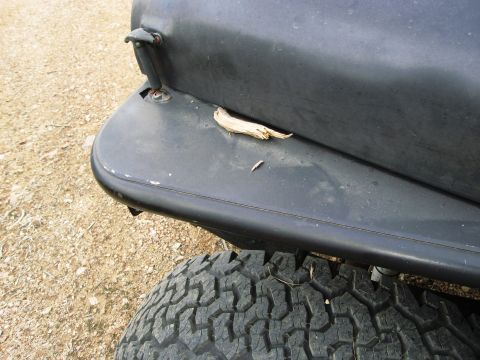 1986 Ford Bronco - A close-up of a vehicle's rear fender and tire, with a piece of wood resting on the fender.