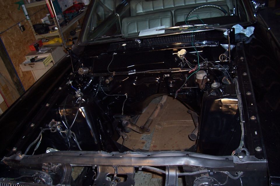 Engine bay of a car stripped of its engine during restoration in a garage