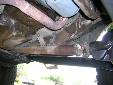 1986 Ford Bronco - Underside view of a vehicle's drivetrain components, including the driveshaft and exhaust pipe.