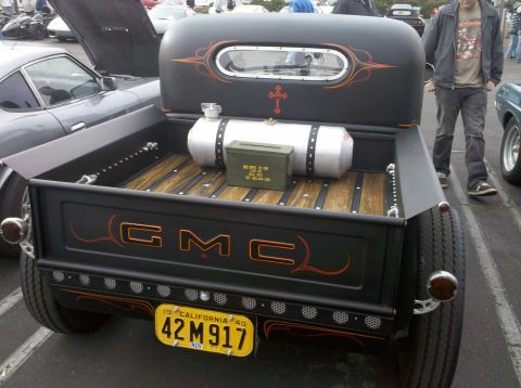 2004 Ford Crown Victoria - A modified GMC pickup truck is seen from the rear, a custom paint job and accessories in its bed.