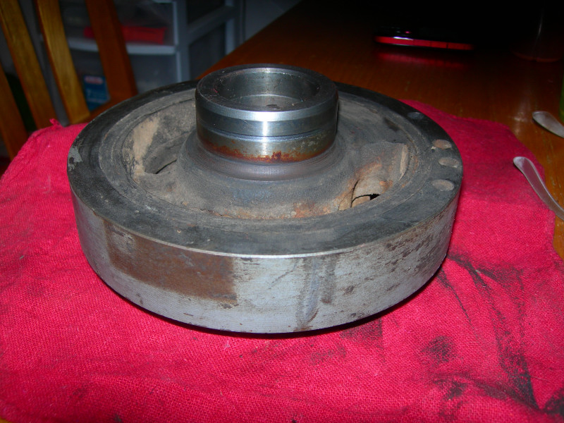 Used crankshaft pulley with rust and wear, resting on a red cloth