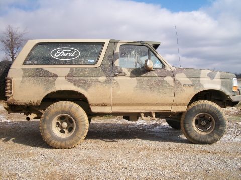 1995 Ford Bronco - This Ford Bronco is covered in mud and sports a camouflage paint job, indicating it's been off-road.