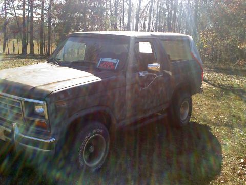1990 Ford Bronco - Camouflaged SUV parked outdoors with a "for sale" sign visible through the windshield.