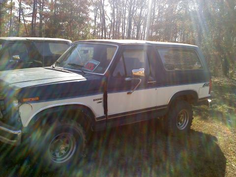 1990 Ford Bronco - This two-tone SUV, possibly a Ford Bronco, is parked outdoors with a "for sale" sign on the windshield.