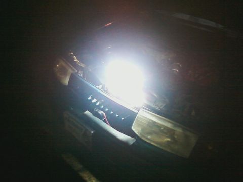 1990 Ford Bronco - Close-up of a vehicle's front end, focusing on a modified headlight with a bright LED bulb.
