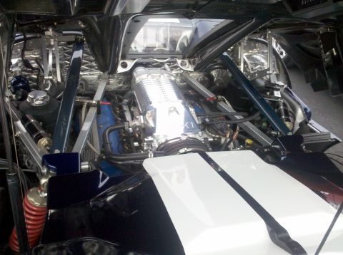 2004 Ford Crown Victoria - The engine bay of a custom vehicle showcases a prominent supercharger and a blue engine block, with a distinctive white hood accented by bl…