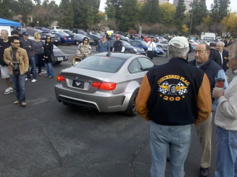 2004 Ford Crown Victoria - A group of people gather around a silver BMW M3 coupe at an outdoor car meet.