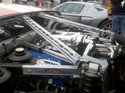 2004 Ford Crown Victoria - Close-up of a custom engine bay with polished components and blue accents, with another vehicle in the background.