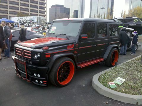 2004 Ford Crown Victoria - Modified black Mercedes-Benz G-Wagen with striking red accents and custom wheels is displayed at an outdoor event.
