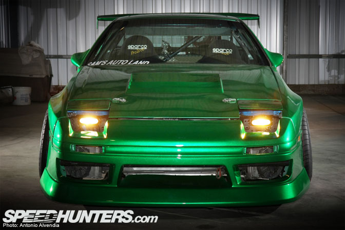 Green 1987 Mazda RX-7 front view with pop-up headlights and custom body kit