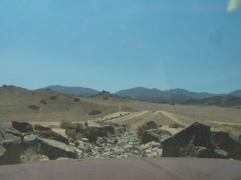 1990 Ford Bronco - The path ahead is blocked by a jumble of large rocks and smaller stones on a dry, dusty terrain.