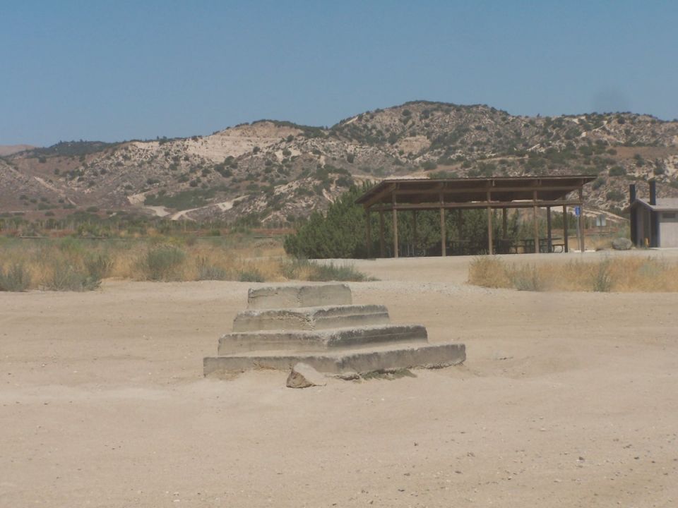Concrete stairs in a dry, dusty landscape with a covered picnic area and hills in the background