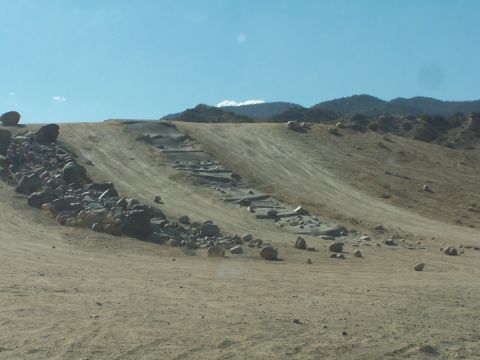 1990 Ford Bronco - The image depicts a barren, rocky landscape with a dirt path leading uphill, suggesting an off-road area.