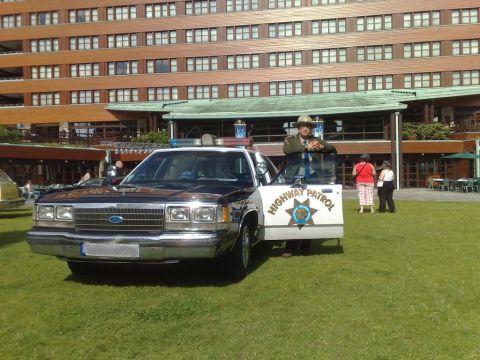 1991 Ford Crown Victoria - A police car with its door open and a person in uniform standing beside it.