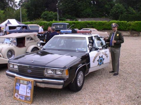 1991 Ford LTD Crown Victoria - 1991 Ford Crown Victoria police car, marked 'HIGHWAY PATROL', with an officer present.