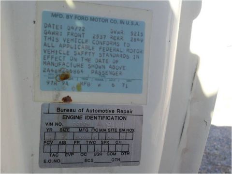1972 Ford Ranchero - Close-up of two vehicle identification plates on a white surface, one showing the date 04/72 and manufacturer information.