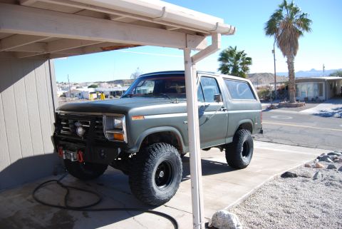 1982 Ford Bronco - This lifted Ford Bronco is parked in a driveway with a palm tree and desert landscape in the background.