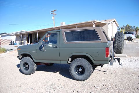 1982 Ford Bronco - A modified Ford Bronco sits parked outside a building under a clear blue sky.