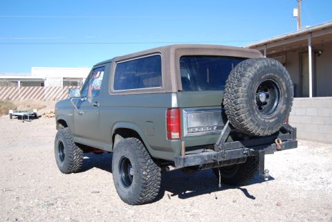 1982 Ford Bronco - This 1982 Ford Bronco is shown from the rear, a spare tire mounted on a custom bumper and a matte green paint job.