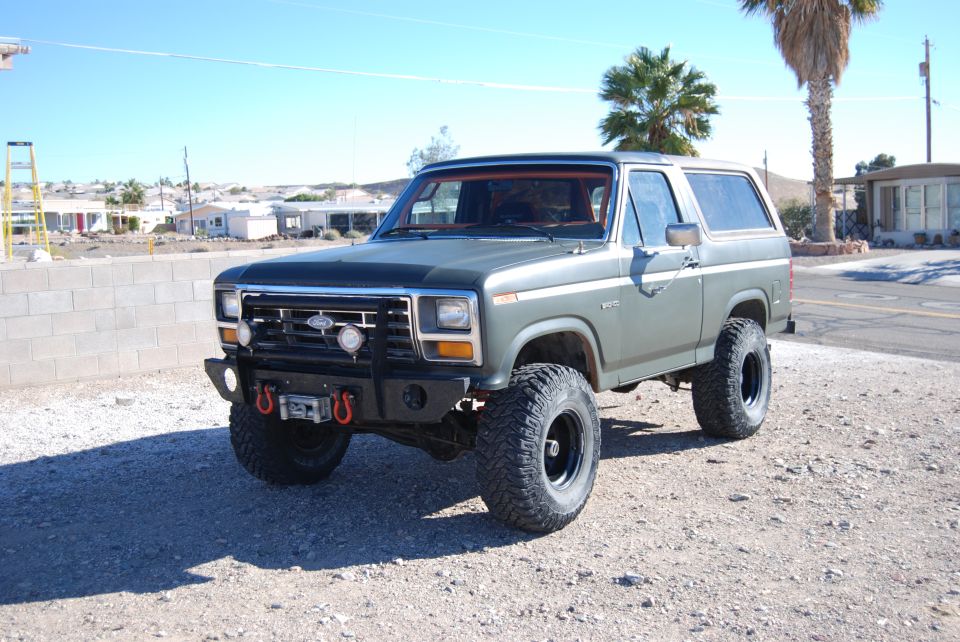 Green Ford Bronco with aftermarket bumper and winch, lifted suspension, and large tires