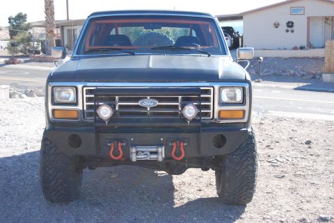 1982 Ford Bronco - This Ford Bronco features an aftermarket bumper with a winch and red tow hooks, along with auxiliary lights on the grille.