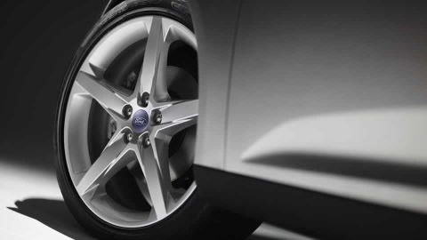 1993 Ford Taurus - A silver 5-spoke wheel with a blue Ford logo center cap is visible on a white vehicle.