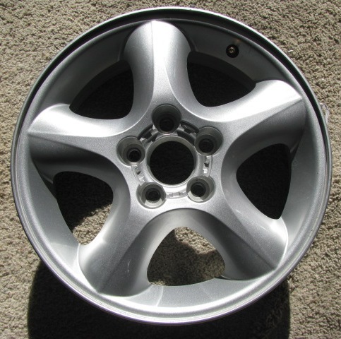 Silver five-spoke car wheel on carpet