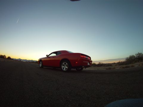 2010 Dodge Challenger - Red Dodge Challenger seen from the rear on a dirt road during sunset.