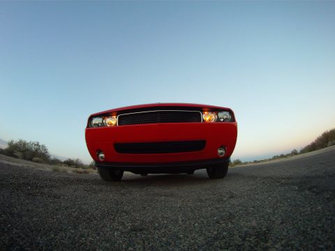 2010 Dodge Challenger - A red Dodge Challenger is seen from the front on a desolate road under a clear sky.