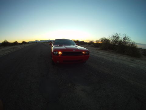 2010 Dodge Challenger - A red Dodge Challenger is parked on a desolate road during a desert sunset.