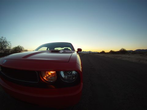 2010 Dodge Challenger - Red Dodge Challenger parked on a dirt road during sunset.