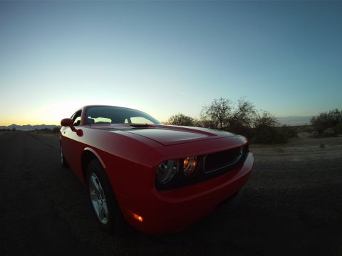 2010 Dodge Challenger - A red Dodge Challenger is parked on a dirt road with desert scenery and a clear sky.