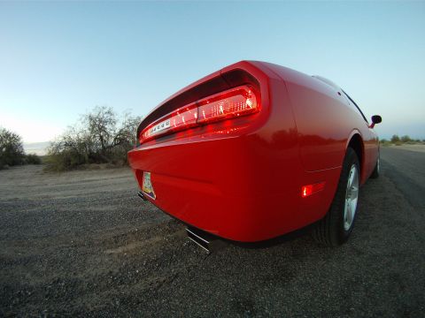 2010 Dodge Challenger - A red Dodge Challenger is parked on a gravel road with a clear sky overhead.