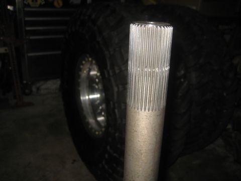1996 Ford Bronco - A close-up view of a splined axle shaft is shown next to a large off-road tire.