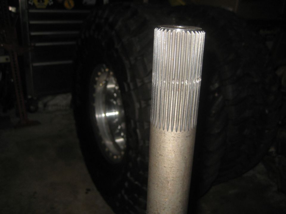 Close-up of a splined axle shaft next to a large tire