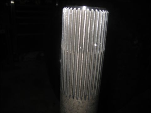 1996 Ford Bronco - Close-up of a splined cylindrical metal shaft end illuminated against a dark workshop background.