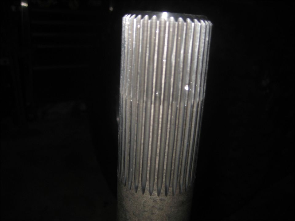 Splined metal shaft end lit in a dark workshop