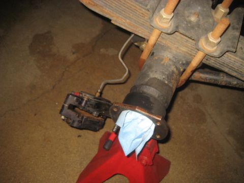 1996 Ford Bronco - Close-up view of a vehicle's rear axle assembly and brake caliper, supported by a red jack stand.