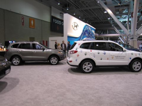 1991 Ford LTD Crown Victoria - A white Hyundai Santa Fe decorated with handprints and text is displayed next to a silver SUV at an auto show.