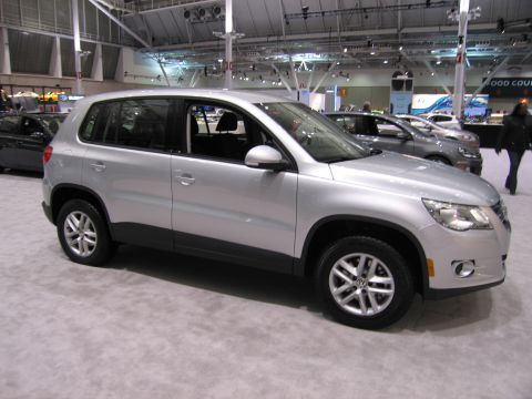 1991 Ford LTD Crown Victoria - A silver Volkswagen Tiguan is displayed at an indoor auto show, with other vehicles visible in the background.