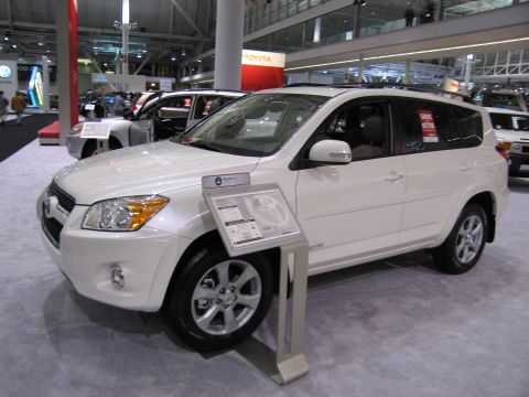 1991 Ford LTD Crown Victoria - A white SUV is displayed at an auto show, with a sign detailing its features and price.