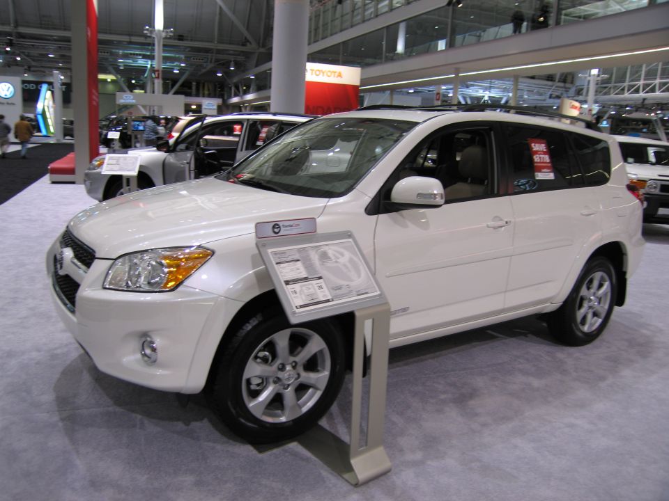 White SUV on display at an auto show with a sign in front of it