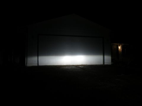 1998 Subaru Legacy - The bright beam of headlights illuminates the lower portion of a closed garage door in the darkness.