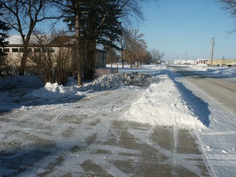 1966 Ford Bronco - A winter scene shows a road and sidewalk covered in snow, with tire tracks visible on the pavement.